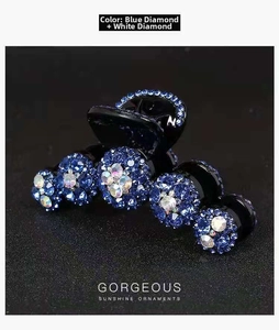 Dettaglio macro della molletta nera con strass blu e bianchi e motivo floreale
