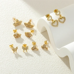 Gold clover butterfly heart earring set with shimmering zircons on white stone pedestal