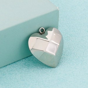 Faceted stainless steel heart pendant in silver finish on a blue textured box