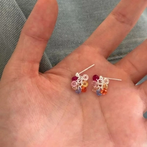 Detail of flower earrings with multi-color crystal beads and silver needles on palm