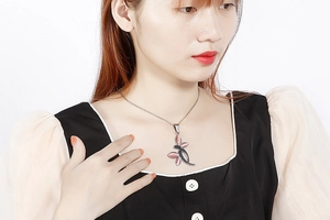 Close-up of a silver necklace with a dragonfly pendant featuring pink gemstones