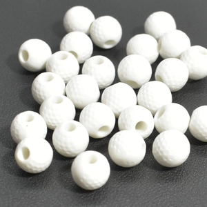 Gros plan détaillé de perles acryliques blanches style golf sur fond texturé noir