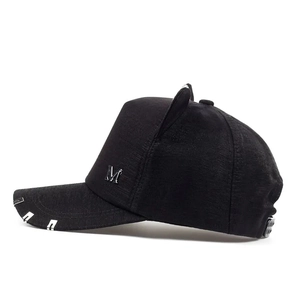 Detail view of black baseball cap with rhinestone cat ears and metal M logo accent