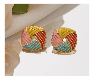 Macro detail of multi-color enamel spiral earrings with golden finish on a mirror