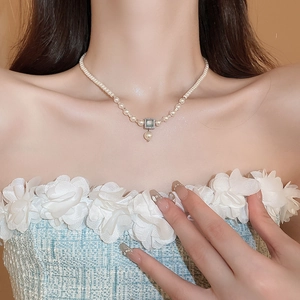 Detail of French pearl necklace with square green gemstone and elegant silver pendant
