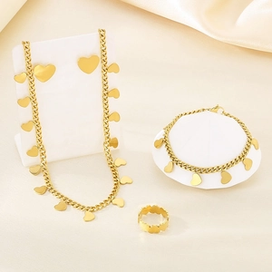 Elegant gold heart jewelry set with necklace, bracelet and ring on silk background