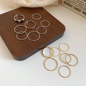 Flat lay detail of 15 pieces minimalist gold and silver ring set on wooden display