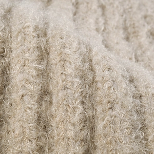 Close-up of warm beige thick knit fabric showing soft fluffy texture of a winter beanie