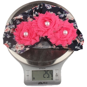 Lightweight floral baby beanie with pink flowers being weighed at 25.4 grams