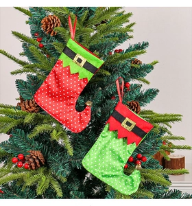 Close-up of red and green elf stockings with gold belts hanging on a Christmas tree