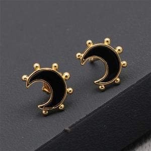Vue macro de boucles d'oreilles lune minimalistes en cuivre doré et émail noir