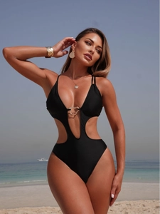 Sexy black one-piece swimsuit with cutout waist and metal buckle detail on beach