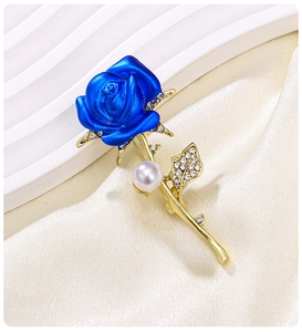 Elegant blue rose brooch with gold metal stem and pearl detail on white background