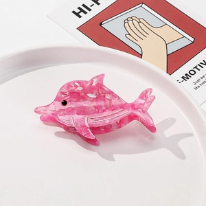 Detail view of a pink acetate dolphin hair claw clip with marble texture on white tray