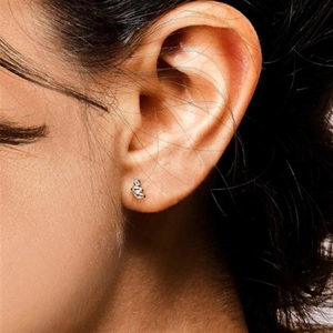 Macro shot of silver flat back cartilage stud earring with heart design on human ear