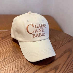 Classic beige cotton baseball cap with embroidered lettering on a wooden surface