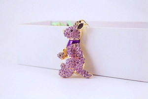 Detail of a gold kangaroo keychain with purple rhinestones and enamel on a white box