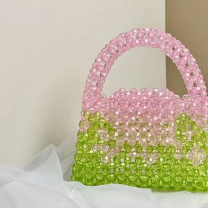 Detailed view of handmade beaded bag in pink and green gradient on soft fabric