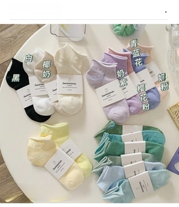 Close-up of colorful cotton ankle socks in pastel shades with card labels on a white surface