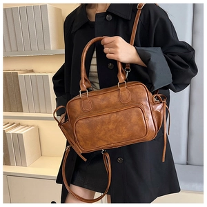Detail of vintage brown leather Boston bag showing handheld handle and adjustable strap