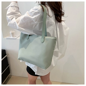Minimalist light green tote bag worn by a model in a clean white studio setting