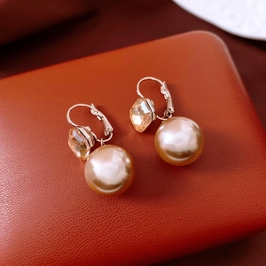 Detailed shot of vintage gold pearl earrings with champagne crystal on leather background