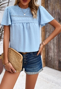 Detail of light blue short sleeve top with lace trim, waist ruffles and dotted texture