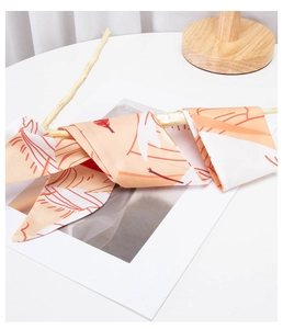 Detail of silk-like ribbon scarf with orange feather patterns wrapped on a wooden branch