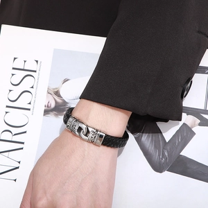 Close-up of black braided leather bracelet with vintage engraved metal clasp on wrist