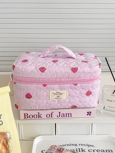 Detailed shot of pink striped quilted makeup bag featuring sweet strawberry print patterns