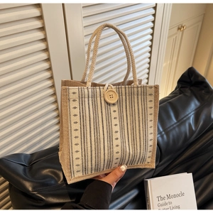 Close-up of striped linen tote bag with wooden button closure and woven rope handle