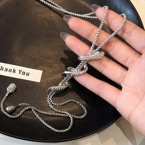 Minimalist silver snake pendant necklace with shimmering diamond accents on a snake chain