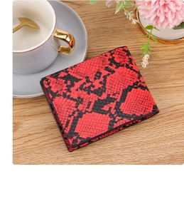 Close-up of red and black snakeskin pattern on a men's bi-fold leather wallet over wood