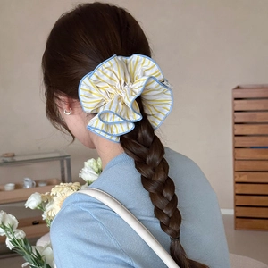 Detail of yellow striped fabric scrunchie worn on a braided hairstyle with blue trim edge