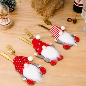 Drie kerstkabouter bestekhouders met gedessineerde mutsen op een feestelijke houten tafel