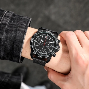 Close-up of a men's black mesh strap watch with a large luminous dial on wrist