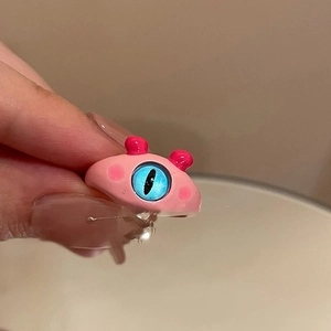 Close-up of a creative pink monster eyeball ring with a unique blue eye design on finger