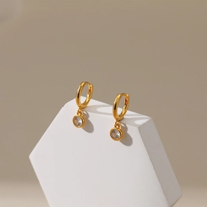 Detail of gold-plated hoop earring featuring a single round zircon stone on a white stand