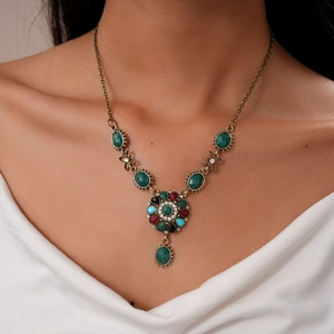 Detailed view of vintage bronze necklace with colorful gemstones on a white shirt