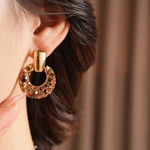 Gros plan d'une boucle d'oreille vintage dorée avec strass ambre sur un mannequin