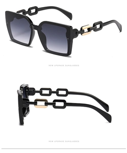 Detail of square oversized sunglasses with black frame and gold chain link temples