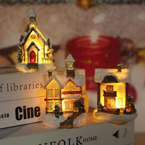 Detail of glowing LED Christmas village house on books with warm festive background