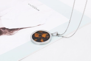 Macro view of round necklace with tortoiseshell resin pendant and silver metal frame