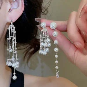 Elegant silver tassel earrings with teardrop pearls and cubic zirconia on a model