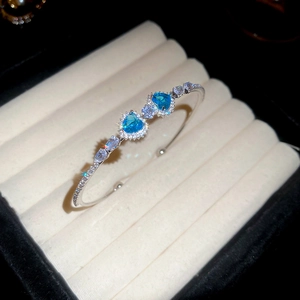 Detail shot of luxury silver heart bangle with blue zircons in a jewelry display box