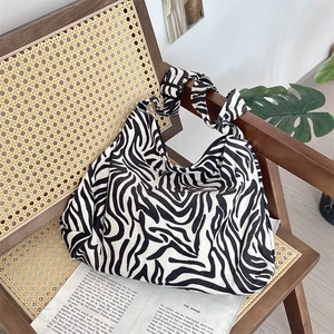 Detail of a zebra print corduroy tote bag displayed on a vintage rattan chair