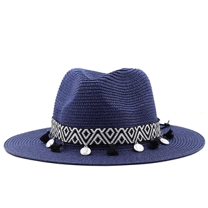 Détail du chapeau en paille bleu marine avec ruban géométrique, franges et pièces argentées