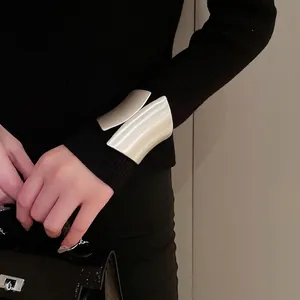 Minimalist wide matte silver open cuff bracelet worn over a chic black knit sleeve