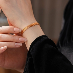 Bracelet en maille plaqué or 18 carats avec une texture métallique tissée sur poignet de femme