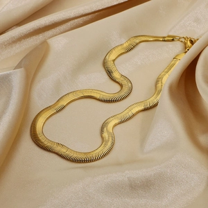Vista dettagliata di una collana piatta a catena serpente dorata su sfondo di seta lussuosa